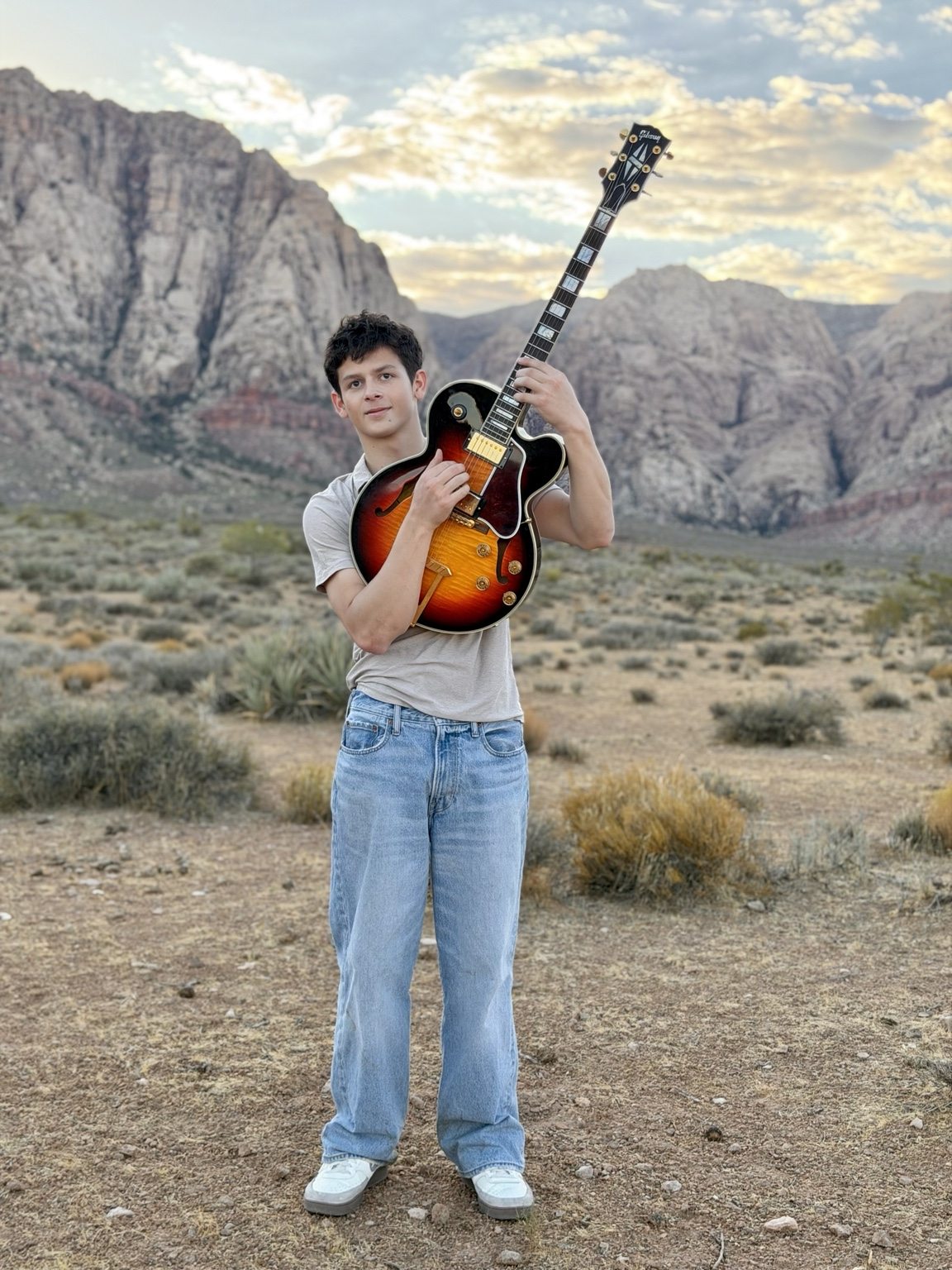 Donnie holding an electric guitar in a desert landscape