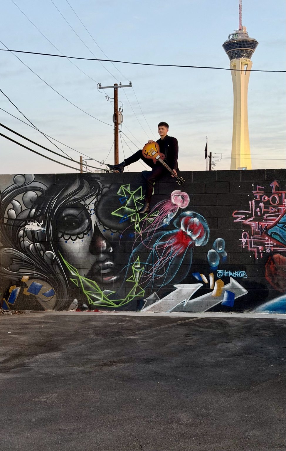 Donnie with a guitar on an urban mural wall