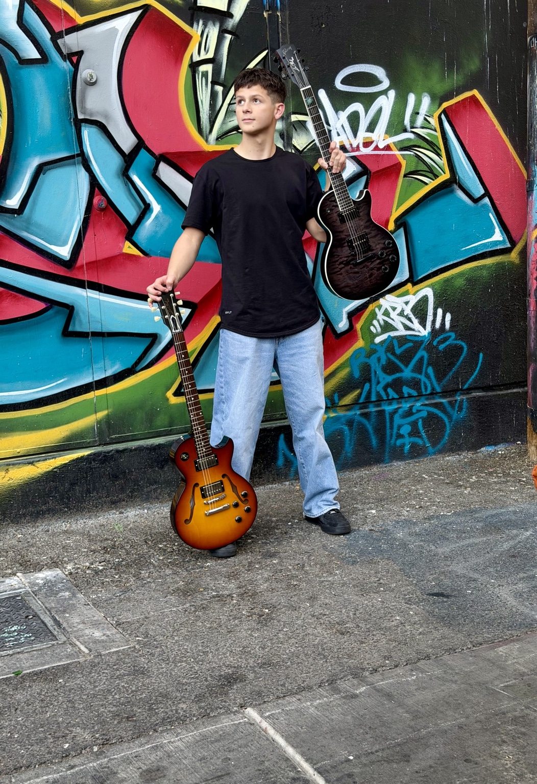 Donnie holding guitars against vibrant street art